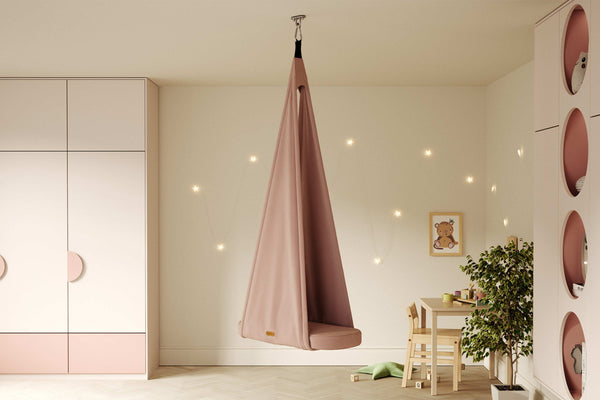 Calm Montessori playroom with pink hanging sensory swing by Jupiduu – soothing indoor hammock chair for toddlers in pastel kids’ room