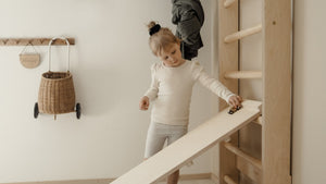 Child playing with FitWood TUOHI Slide made from sustainable birch wood, promoting independent play. Girl Rolling Car down smooth side of slide.