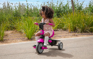Toddler independently riding a pink smarTrike tricycle - designed for safe and fun outdoor play by Little Gliders