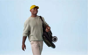 Man carrying a foldable smarTrike stroller - compact and travel-friendly baby gear by Little Gliders