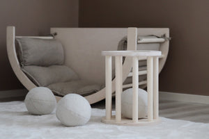 A minimalist playroom with a soft padded wooden seat and large fabric balls, showcasing Scandinavian design and child-friendly furniture perfect for creative play. Fitwood luoto stool little gliders