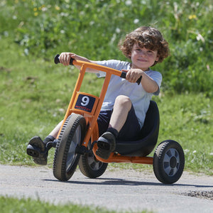 A boy riding the Winther orange Easy Rider trike, enjoying a low-seated design for active and comfortable outdoor play – available at Little Gliders.