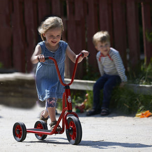 A young girl riding the Winther red twin wheel scooter, fostering balance, coordination, and outdoor fun – available at Little Gliders.