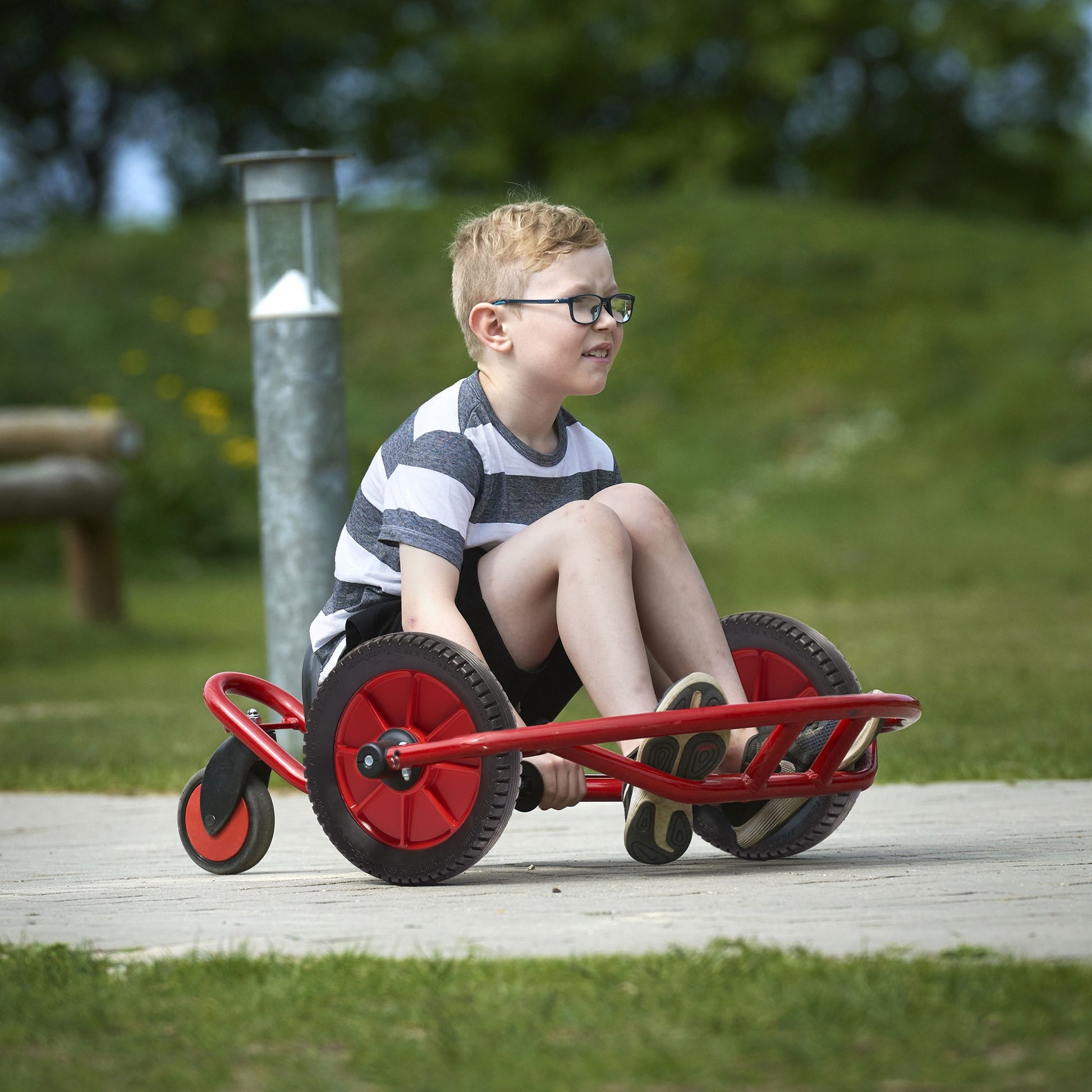 A boy riding the red Winther FunCart, designed for exciting and active outdoor play, encouraging balance and coordination – available at Little Gliders.
