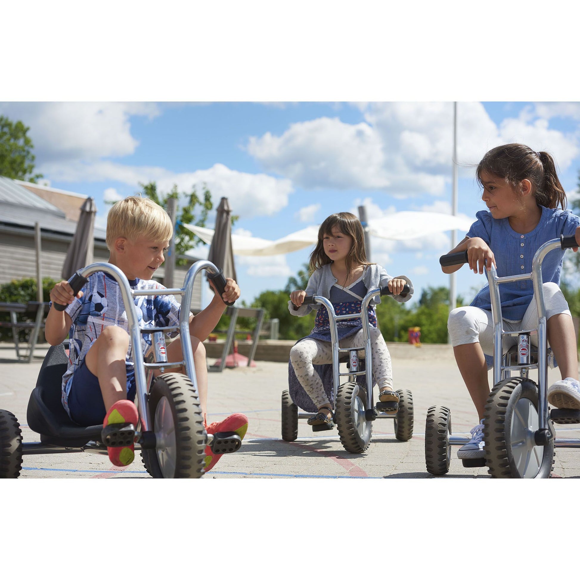 Three children riding Winther Viking trikes together, enjoying collaborative outdoor fun and developing motor skills – available at Little Gliders.