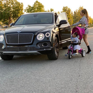 Telli Swift steps out of a Bentley SUV as her child rides a matching Bentley 6-in-1 Trike in fuchsia pink—where luxury meets parenting.