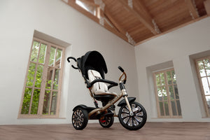 Bentley 6-in-1 Trike in Gold displayed in a luxury interior with wooden flooring and tall windows, showcasing elegant design and premium detailing.