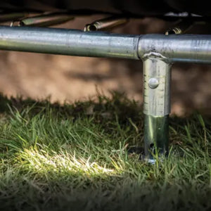 Sturdy galvanised steel frame leg of BERG trampoline anchored in grass, designed for long-lasting outdoor use.