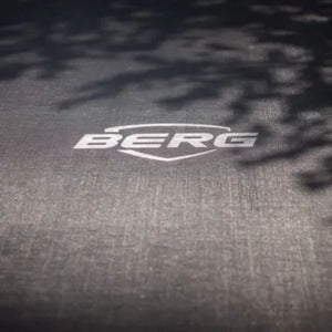 Close-up of BERG trampoline jumping mat with logo, featuring durable UV-resistant material for outdoor garden play.