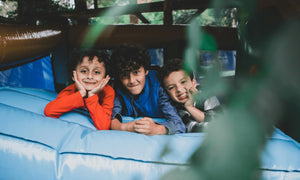 Three smiling boys lying on an inflatable play structure – ideal for parents looking for kids' play equipment, outdoor adventure gear, and safe playtime essentials for children.