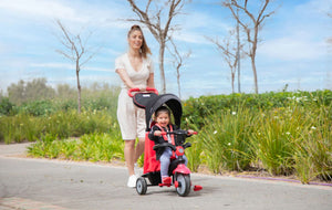 Toddler independently riding a pink smarTrike tricycle - designed for safe and fun outdoor play by Little Gliders