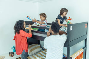 Happy family playing together in a child’s bedroom, with two children on a black bunk bed enjoying toys while parents engage and smile – perfect for kids' bedroom inspiration and playful family moments in the UK