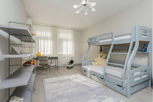 Light grey Noomi triple stack bunk bed in a spacious, modern children's bedroom with built-in storage drawers and a tidy study area – ideal space-saving kids’ bed solution.