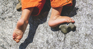 Close-up of a child’s bare feet climbing on textured stone, symbolising balance, movement and physical play development