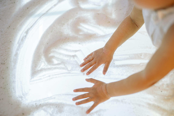 Close-up of toddler hands exploring sensory sand on a light table – early years sensory play for calm, focus and tactile development