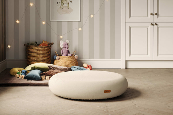 Neutral kids' playroom with round soft pouf by Jupiduu – toddler-friendly floor cushion with plush toys, cushions and calming decor for sensory and quiet play