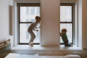 Two young siblings playing near a window in a cosy shared bedroom, symbolising connection and smart use of space in family homes.