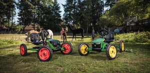 Two BERG Buddy go-karts in a scenic farm setting with alpacas in the background, showcasing their vibrant colours and sturdy design for outdoor play.
