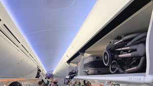 Compact stroller neatly stored in airplane overhead bin, demonstrating easy travel convenience.