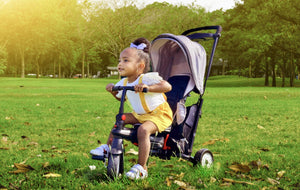 Child riding smarTrike stroller trike in a grassy field - comfortable and versatile trike for outdoor exploration by Little Gliders