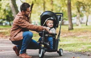 Father adjusting smarTrike stroller trike for his child in a park - the perfect trike for family outings by Little Gliders