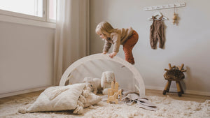 A child playing on the FitWood play arch, made from sustainable birch wood, designed for active play and development. Perfect for encouraging imaginative play in a stylish Nordic-inspired space.