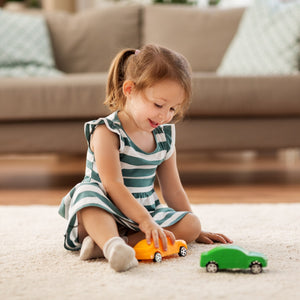 Young girl playing with toy cars on rug – Little Gliders 1-3 year collection