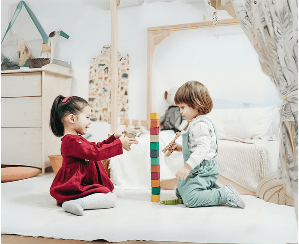 Two toddlers playing with wooden stacking blocks and toy animals in a beautifully decorated nursery – perfect for parents looking for Montessori toys, sustainable nursery furniture, and interactive playtime ideas.