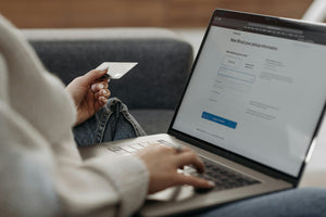 Person holding a credit card while entering checkout details on a laptop, highlighting online shopping convenience.
