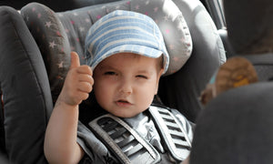 Toddler in secure car seat smiling with thumbs up – Little Gliders baby safety gear