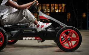 Close-up side profile of a black BERG go-kart with bold red wheels, showcasing sporty design and performance.