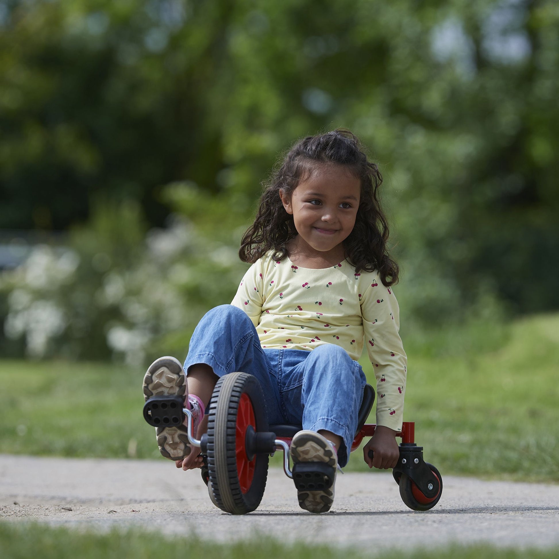 A young girl riding a Winther FunCart outdoors, enjoying active play and building coordination skills – available at Little Gliders.