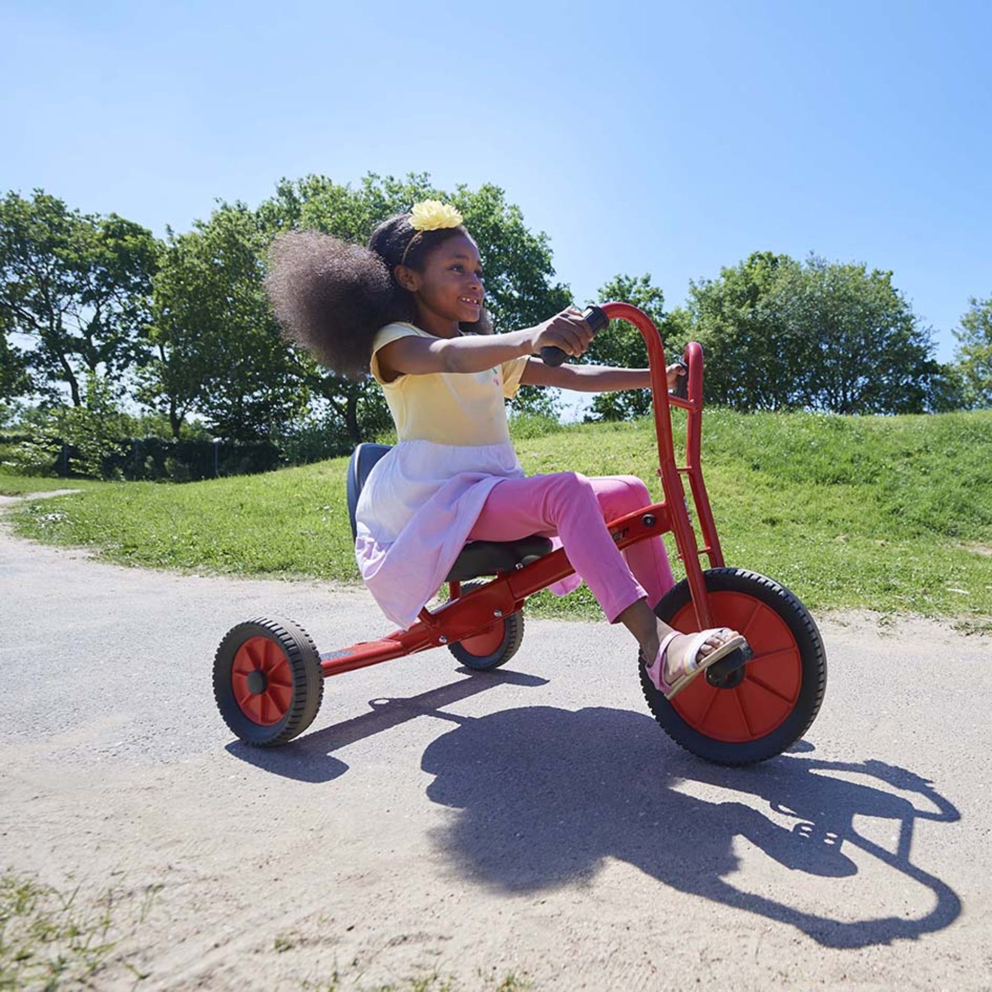 A girl enjoying a sunny day while riding the adjustable Winther Viking Tricart, perfect for active outdoor play and motor skill development – available at Little Gliders.